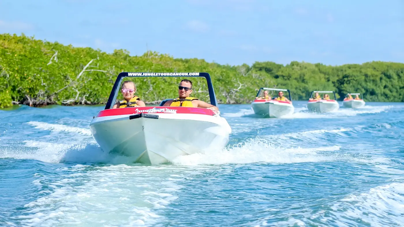 A caravan of three Jungle Tour adventure speedboats sailing through the mangrove canals in Cancun.
